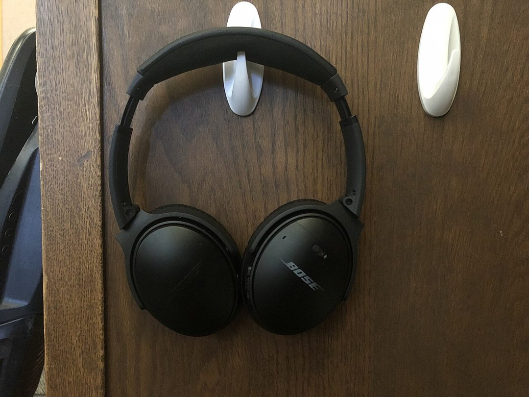 Black Bose QuietComfort headphones hanging on a hook